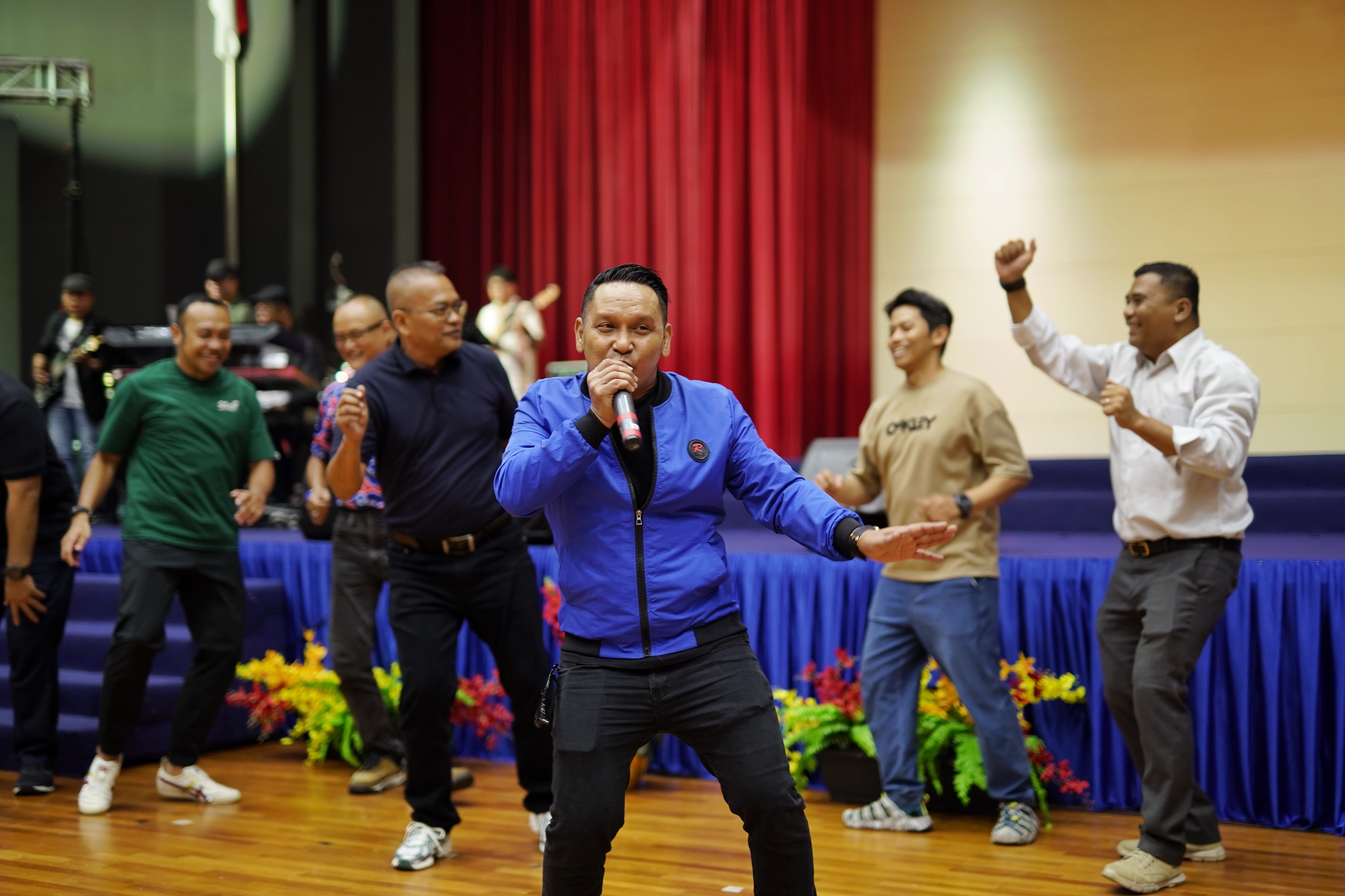 A singer performs with a microphone while attendees dance and move along with music.